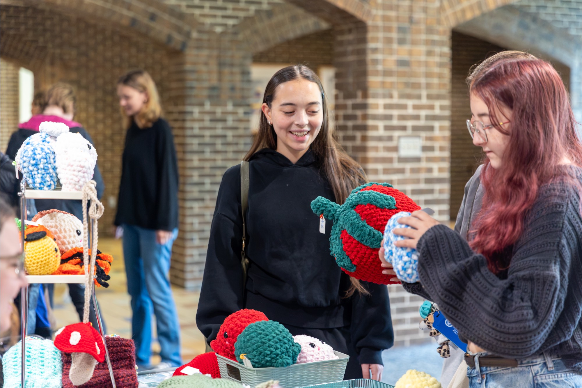 two girls holding a crocheted strawberry